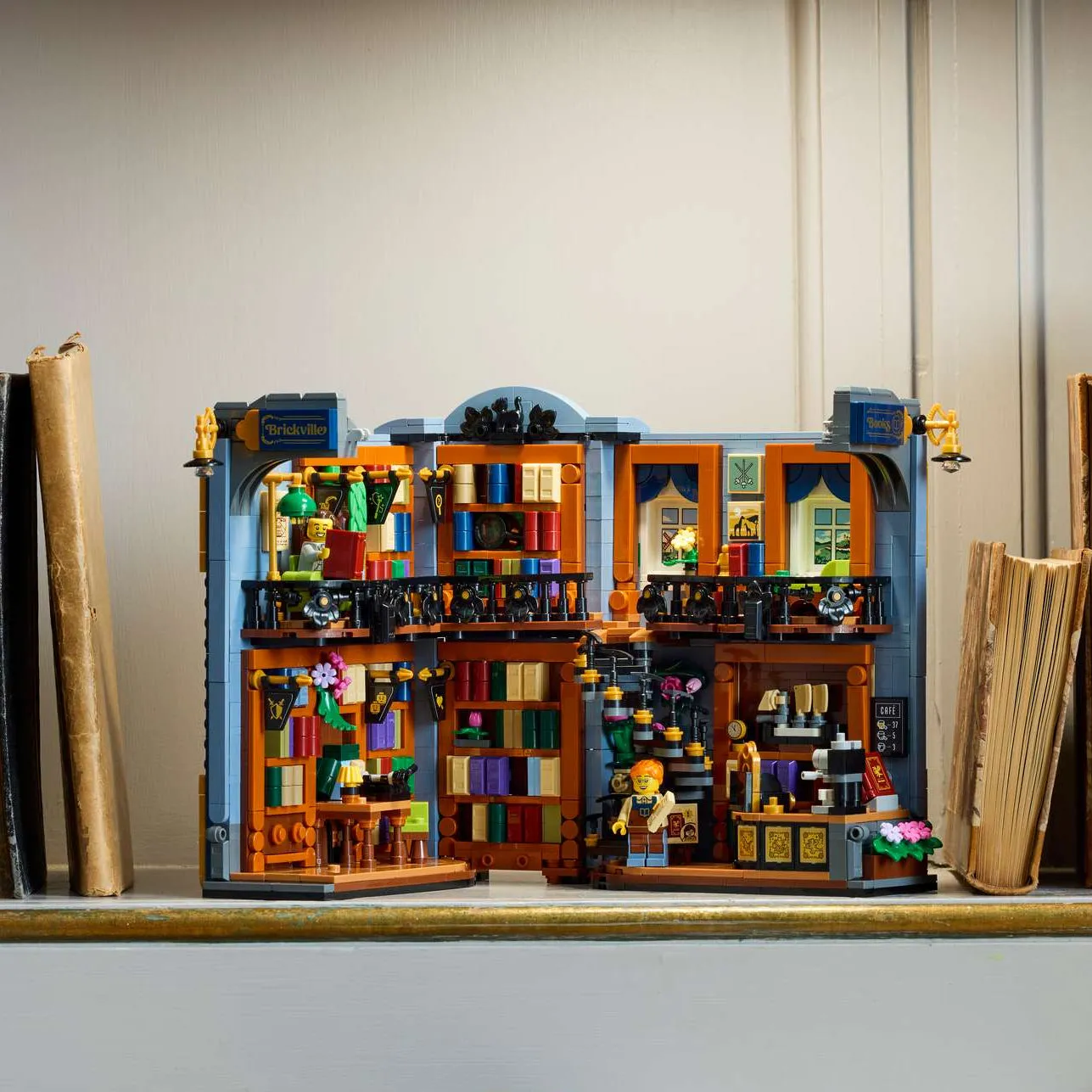 A LEGO bookshop model set with lit windows on a shelf between two book ends