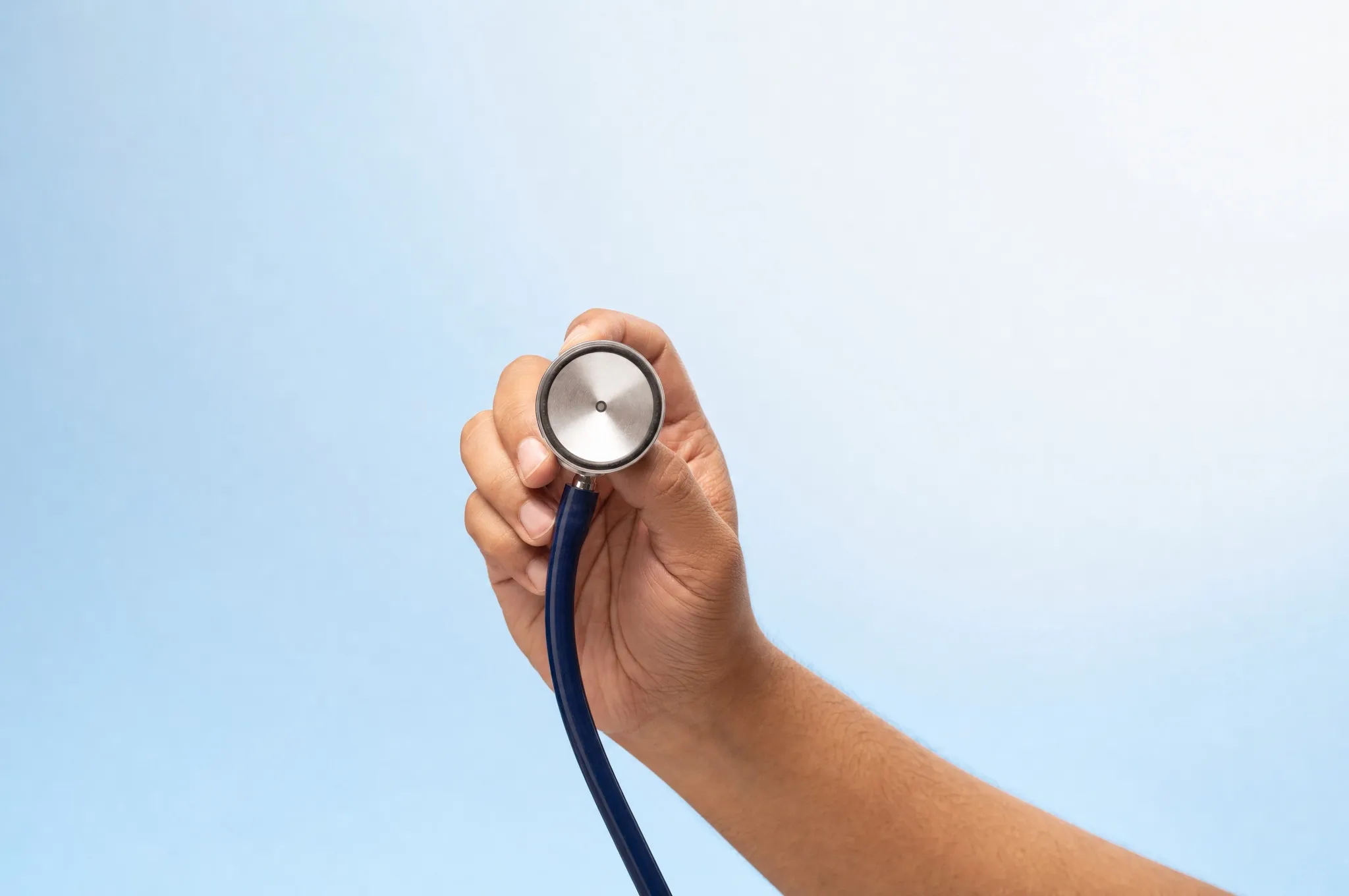 A hand holding the chest piece of a stethoscope