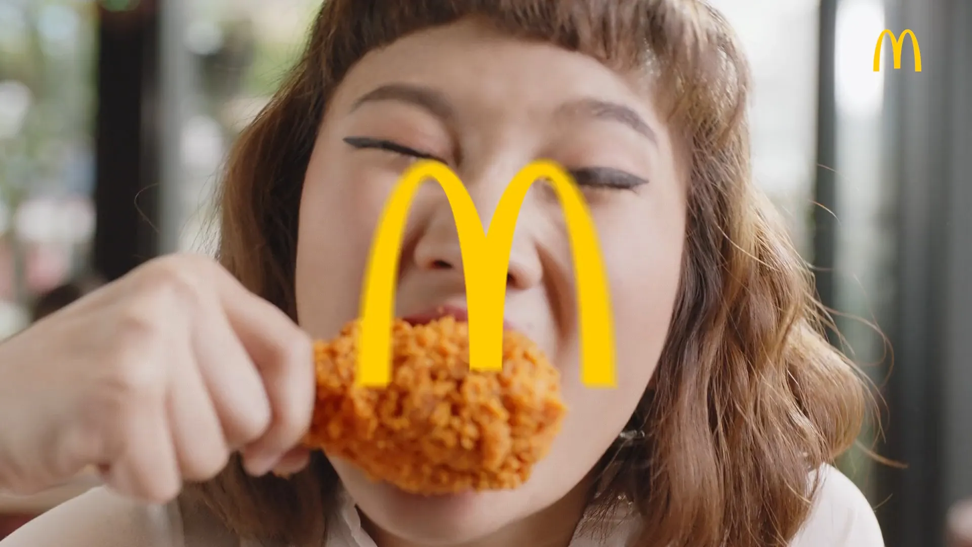 A woman eating McDonald’s chicken, the golden arches framing the shot