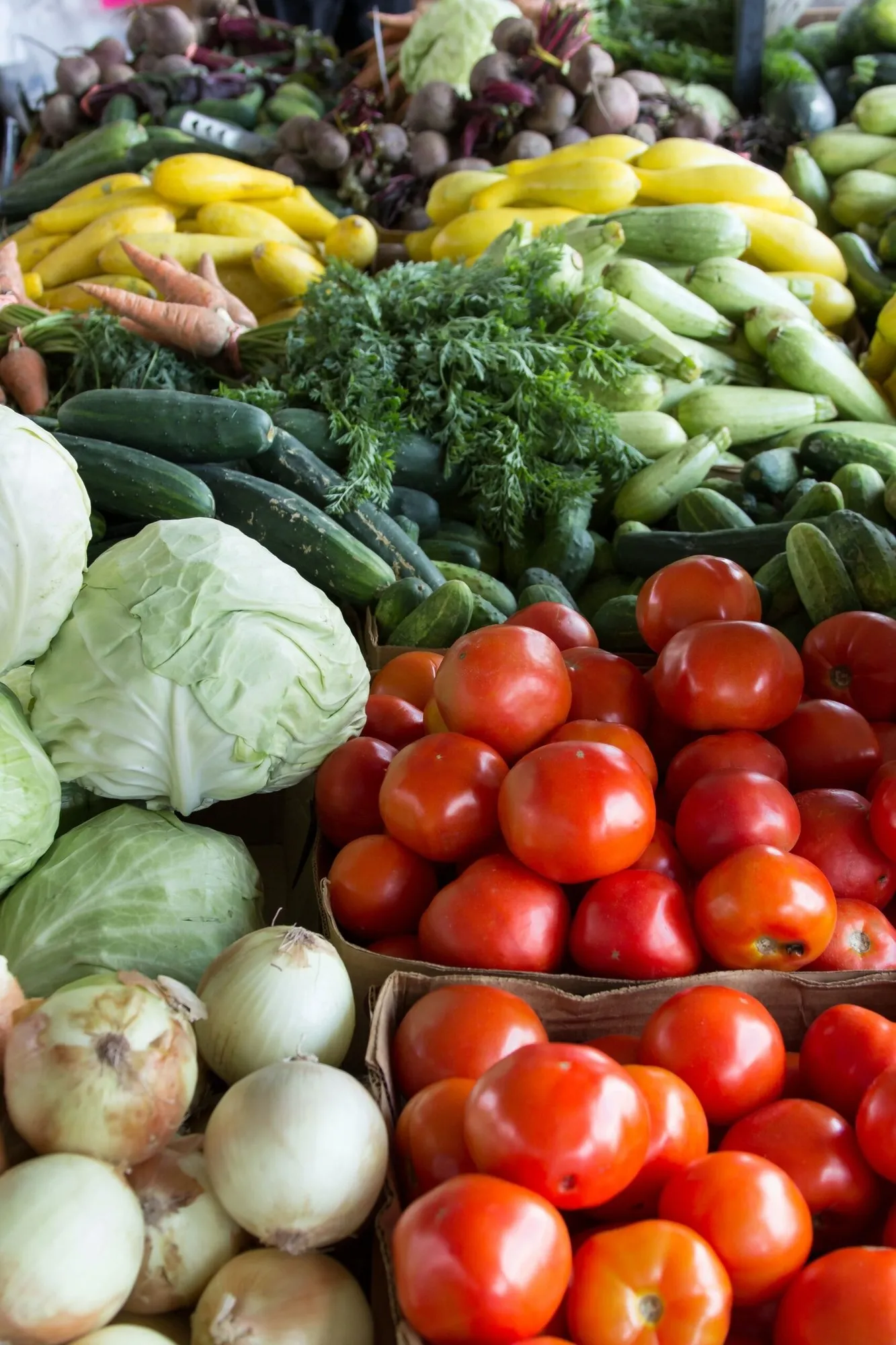 A market display of fresh vegetables, cabbages and tomatoes