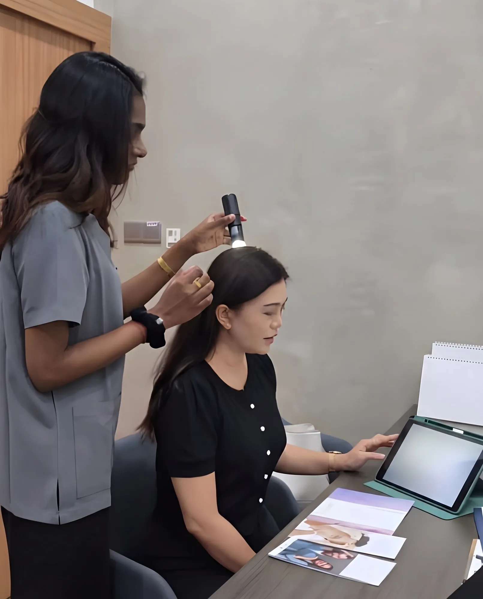 An Ozhean A.M Clinic consultant examining a patient’s scalp at a desk