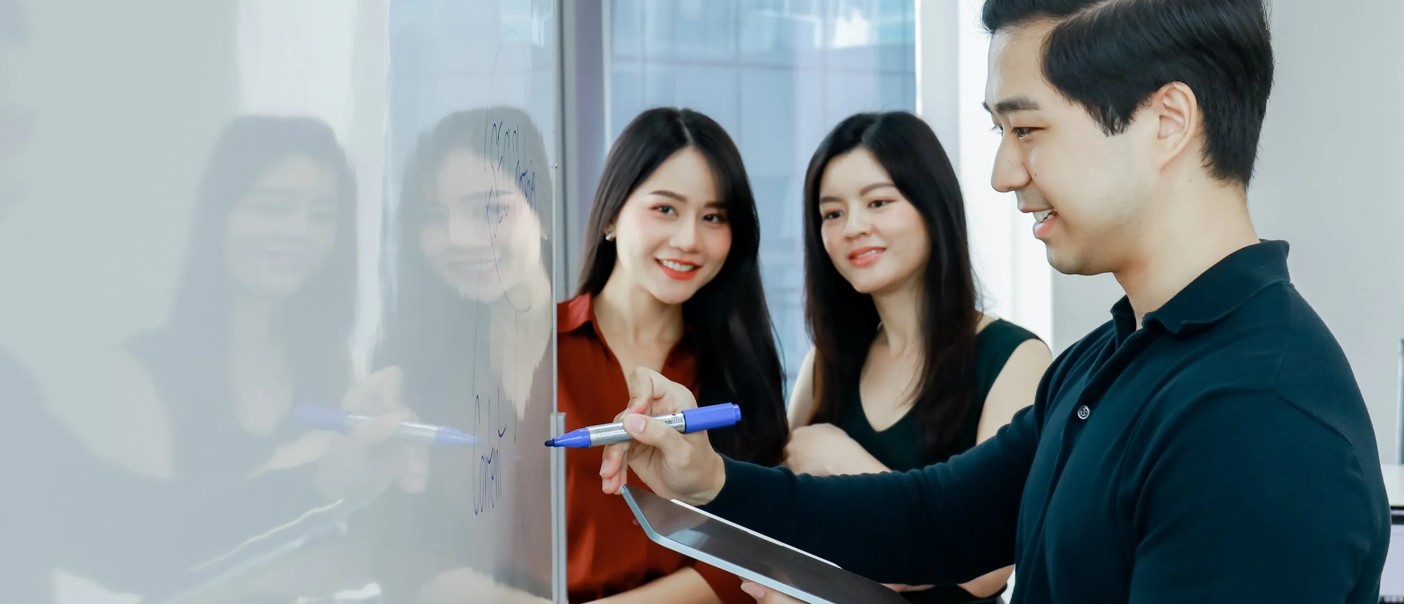 Three Primal colleagues writing on a glass wall together
