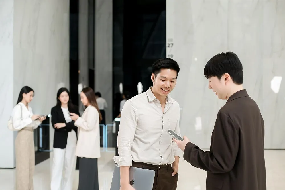 Primal colleagues talking in an office lobby, one holding a phone