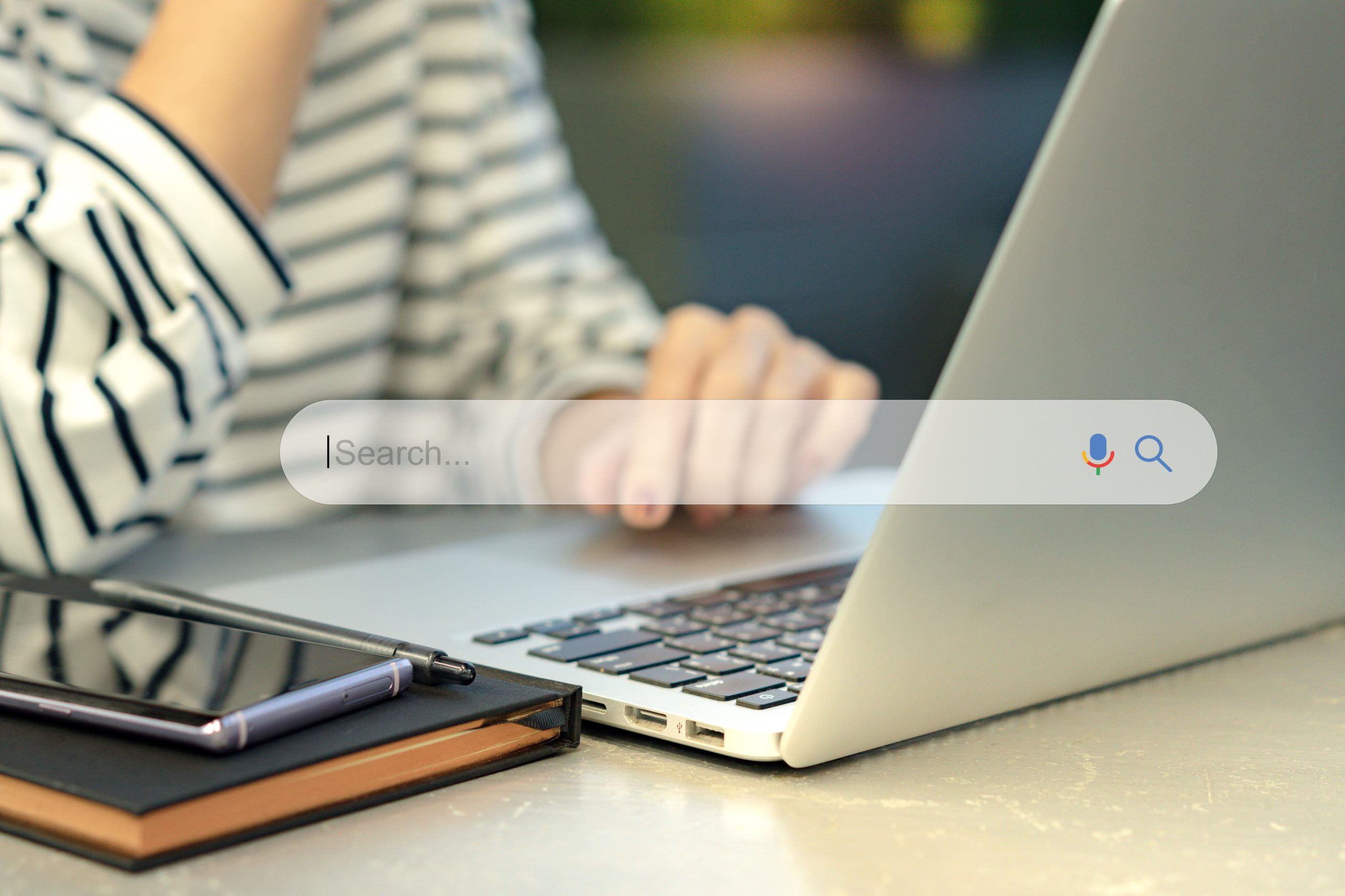 A Malaysian businesswoman using AI search on a laptop. Google AI Overviews is a notable part of it.